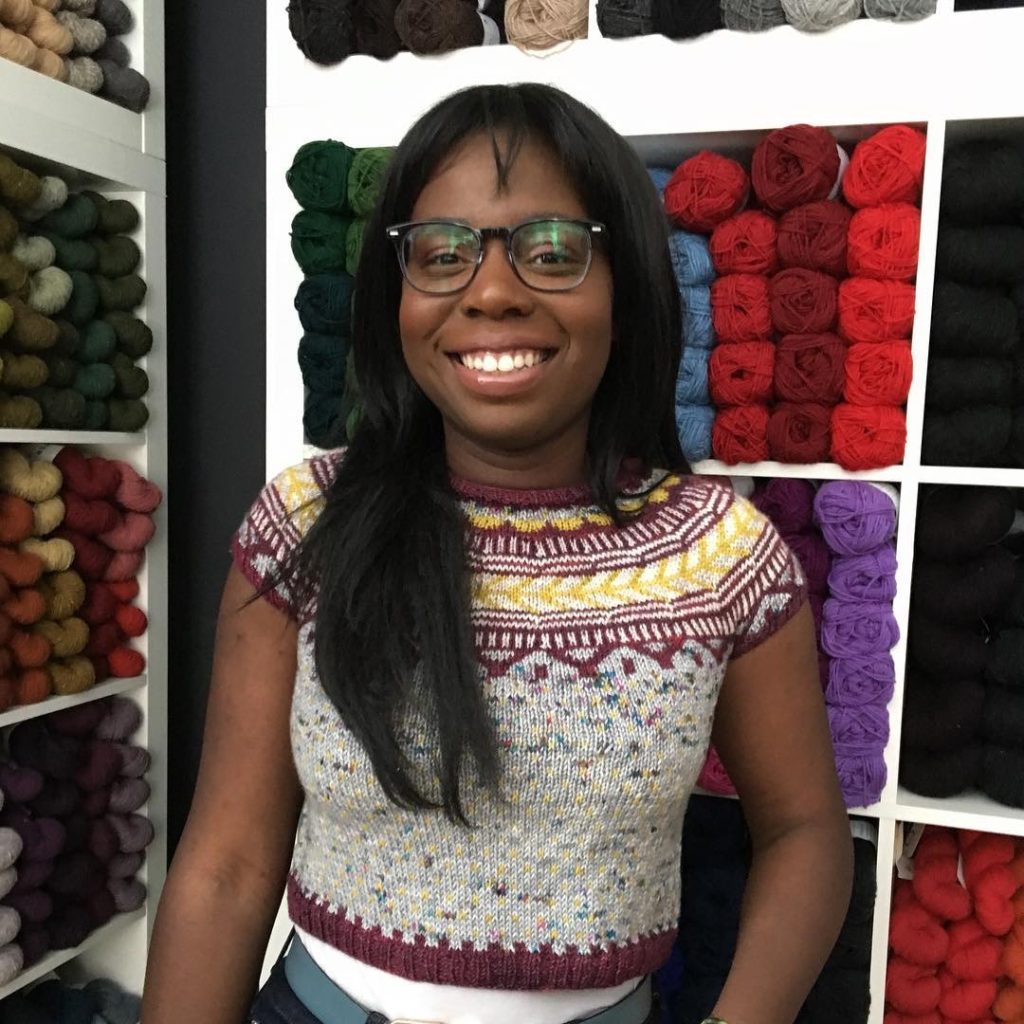 African Canadian woman standing in front of a wall of yarn
